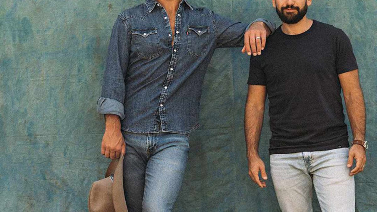 Two country artists posing in front of a painted wall