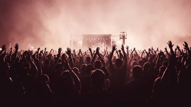 Concert crowd with hands in the air under stage lights